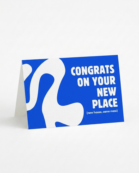 A blue and white folding card with the text 'CONGRATS ON YOUR NEW PLACE (new house, same mess)' displayed on a clean white background.